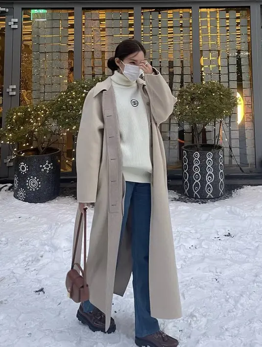 Pemilik nama asli Park Sun-young ini tampil mengenakan coat warna nude dipadukan sweater turtleneck putih dari Chanel. Dikombinasikan dengan celana denim, sepatu oxford, dan sling bag cokelat. (@hyominnn)