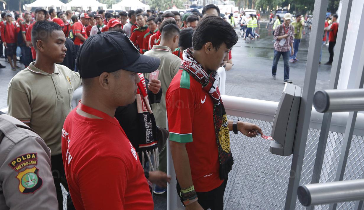 Seorang suporter menempelkan tiket ke mesin barcode saat memasuki SUGBK, Senayan, Jakarta, Minggu (14/1/2018). Fasilitas baru tersebut untuk meningkatkan keamananan, kenyamanan serta kedisiplinan suporter. (Bola.com/M Iqbal Ichsan)