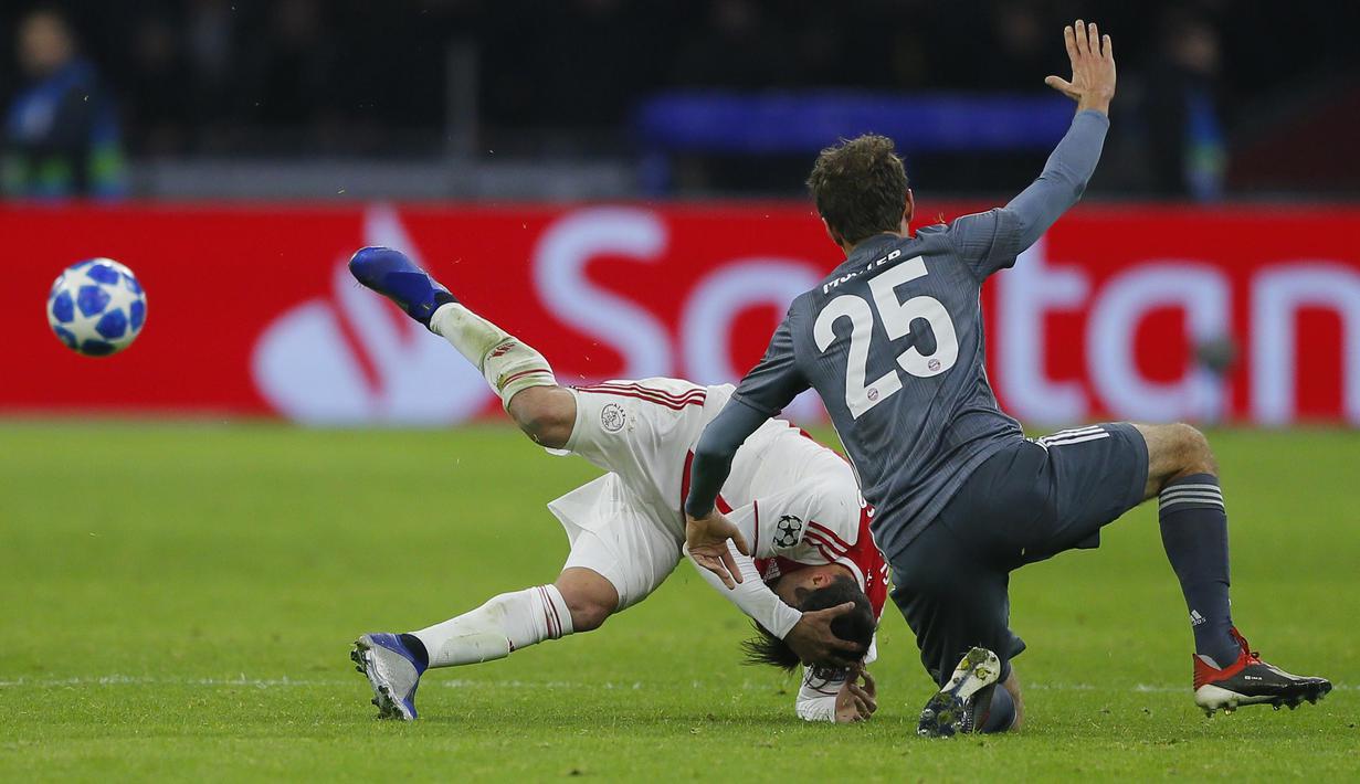 Bek Ajax Amsterdam, Nicolas Tagliafico, terjatuh usai ditendang gelandang Bayern Munchen, Thomas Mueller, pada laga Liga Champions di Johan Cruyff Arena, Amsterdam, Rabu (12/12). Kedua tim bermain imbang 3-3. (AP/Peter Dejong)