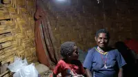 Seorang ibu dan anaknya duduk di bawah Lampu Tenaga Surya Hemat Energi (LTSHE) di Distrik Puldama, Kabupaten Yahukimo, Provinsi Papua. LTSHE bisa dinyalakan secara manual lewat tombol di lampu atau dengan remote control. (Liputan6.com/HO/Hadi M Juraid)