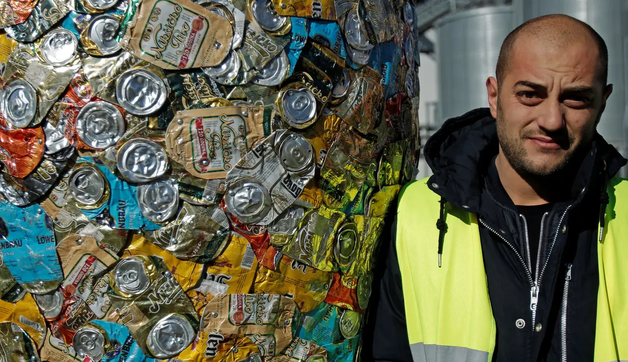 Marko Petrovic Njegos berpose disamping patung ciptaannya  'Bottle and glass' di Niksic, Montenegro, Senin (31/10). Patung karya dirinya dan seniman Nikola Simanic itu terbuat dari ribuan kaleng bir. (REUTERS / Stevo Vasiljevic)