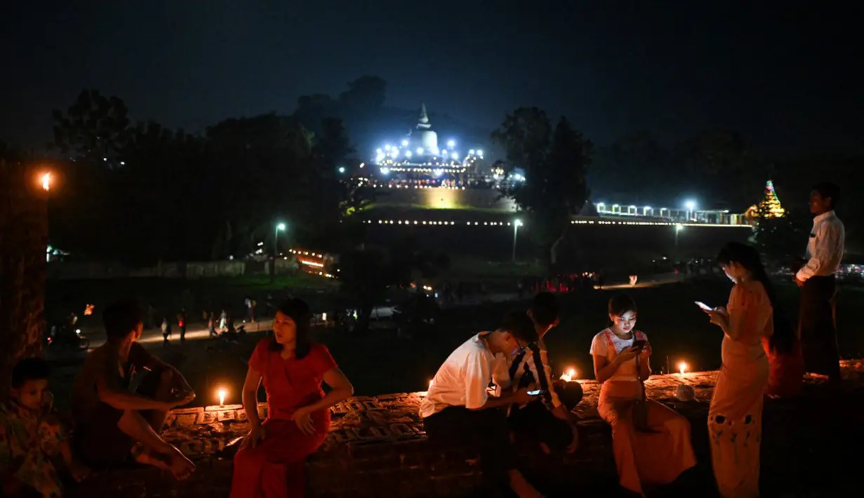 Orang-orang mengambil bagian dalam Festival Tazaungdaing di pagoda di Mrauk U, Rakhine, Myanmar, 18 November 2021. Tazaungdaing adalah Festival Bulan Purnama yang diadakan setiap tahun pada bulan purnama, bulan kedelapan dalam kalender Burma. (STR/AFP)