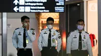 Petugas Imigrasi bandara menggunakan masker pelindung saat berada di Pintu Kedatangan Terminal 3 Ultimate Bandara Soekarno Hatta, Tangerang, Jumat (31/1/2020). Hal itu dilakukan sebagai antisipasi penularan dan penyebaran virus corona (2019-nCov). (Liputan6.com/Johan Tallo)