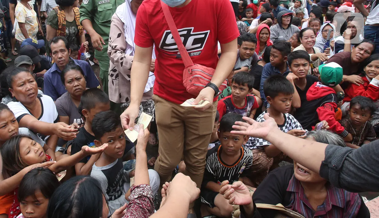 Seorang pria membagikan angpao kepada pengemis di halaman Vihara Dharma Bhakti, Petak Sembilan, Jakarta Barat, Sabtu (25/1/2020). Pembagian Angpao tersebut dalam rangka berbagi dengan sesama ketika perayaaan Tahun Baru Imlek 2571. (Liputan6.com/Angga Yuniar)