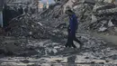 Warga Palestina berjalan di tengah bangunan yang hancur akibat serangan udara dan darat Israel di Kota Gaza, Selasa 6 Januari 2026. Komite Internasional Palang Merah (ICRC) terus berupaya menyalurkan bantuan ke Gaza. (AP Photo/Jehad Alshrafi)