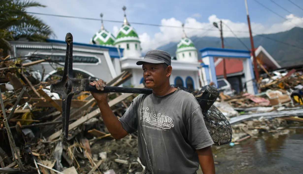 Warga membawa kipas angin yang diselamatkan dari sebuah pasar yang runtuh setelah gempa dan tsunami di  Palu, Kamis (4/10). BNPB menyebut, hingga Kamis sore, jumlah korban meninggal akibat gempa dan tsunami Palu mencapai 1.558 orang. (AFP/Jewel SAMAD)