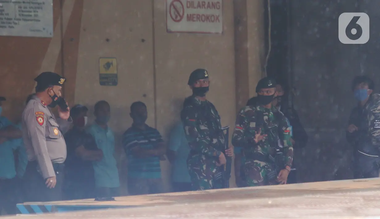 Personel TNI dan aparat kepolisian berjaga saat penjemputan vaksin Covid-19 Sinovac di Terminal Kargo Bandara Soekarno-Hatta, Tangerang, Kamis (31/12/2020). TNI dan Polri diterjunkan mengawal kedatangan vaksin Covid-19 dari Bandara Soetta menuju PT Bio Farma di Bandung. (Liputan6.com/Angga Yuniar)