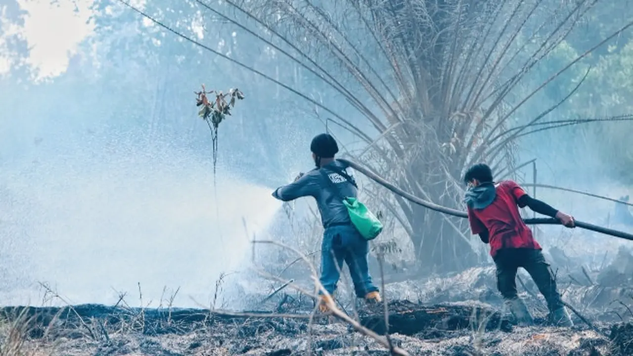 Petugas memadamkan kebakaran lahan di Suaka Margasatwa Giam Siak Kecil yang disengaja dibakar untuk pembukaan kebun.