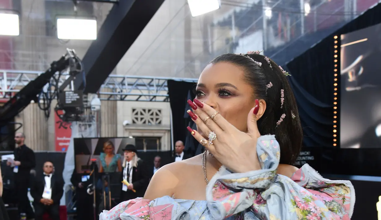 Penyanyi Andra Day menyapa para penggemarnya sesaat sebelum berjalan di karpet merah penghargaan Piala Oscars 2018 di Dolby Theatre, Los Angeles, Minggu (4/3). Andra Day menyempurnakan penampilannya dengan clutch abu-abu. (Charles Sykes/Invision/AP)