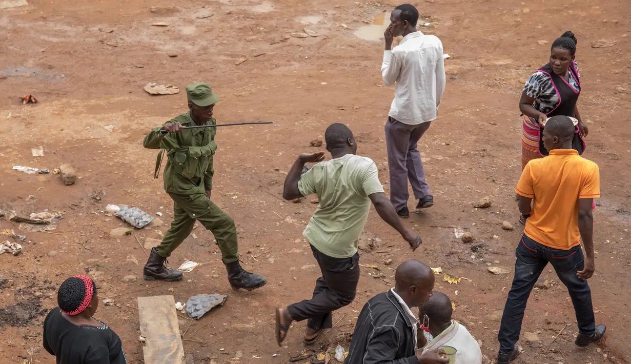Aparat kepolisian memukuli pria saat membubarkan orang-orang yang masih berkeliaran di Kampala, Uganda (26/3/2020). Presiden Uganda Yoweri Museveni mengimbau masyarakatnya untuk tinggal di rumah selama 32 hari setelah 14 kasus positif Covid-19 teridentifikasi di negara tersebut. (AFP/Badru Katumba)