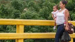 Perempuan Venezuela menenteng bahan makanan yang dibeli di Kolombia, ketika berjalan pulang menuju perbatasan di Cucuta, Rabu (6/7). Krisis ekonomi yang melanda Venezuela membuat warga menerobos perbatasan masuk ke wilayah Kolombia (Schneyder MENDOZA/AFP)