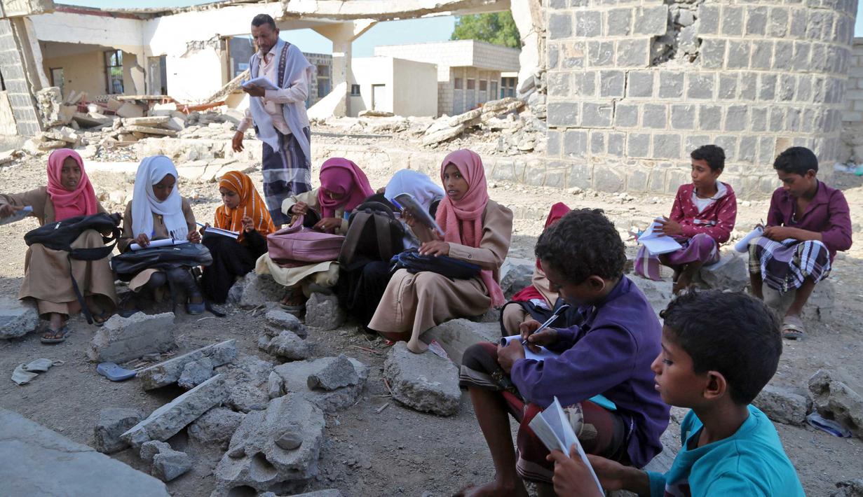 Anak-anak Yaman menghadiri kelas di luar ruangan sebuah sekolah yang rusak parah pada hari pertama tahun ajaran baru di provinsi barat Yaman yang dilanda perang Hodeida, Senin (17/10/2022). UNICEF memperkirakan bahwa lebih dari dua juta anak telah putus sekolah di Yaman, peningkatan hampir setengah juta sejak perang pecah pada 2015. (Foto oleh Khaled ZIAD / AFP).