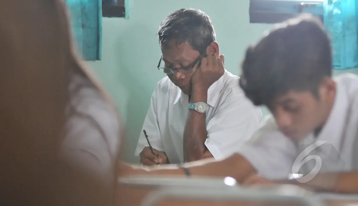 Seorang pria terlihat mengerjakan soal Ujian Nasional (UN) kesetaraan paket B di SMPN 80 Jakarta, Senin (4/5/2015). Sebanyak 378 peserta, termasuk peserta berusia lanjut mengikuti UN di hari pertama tersebut. (Liputan6.com/Johan Tallo)