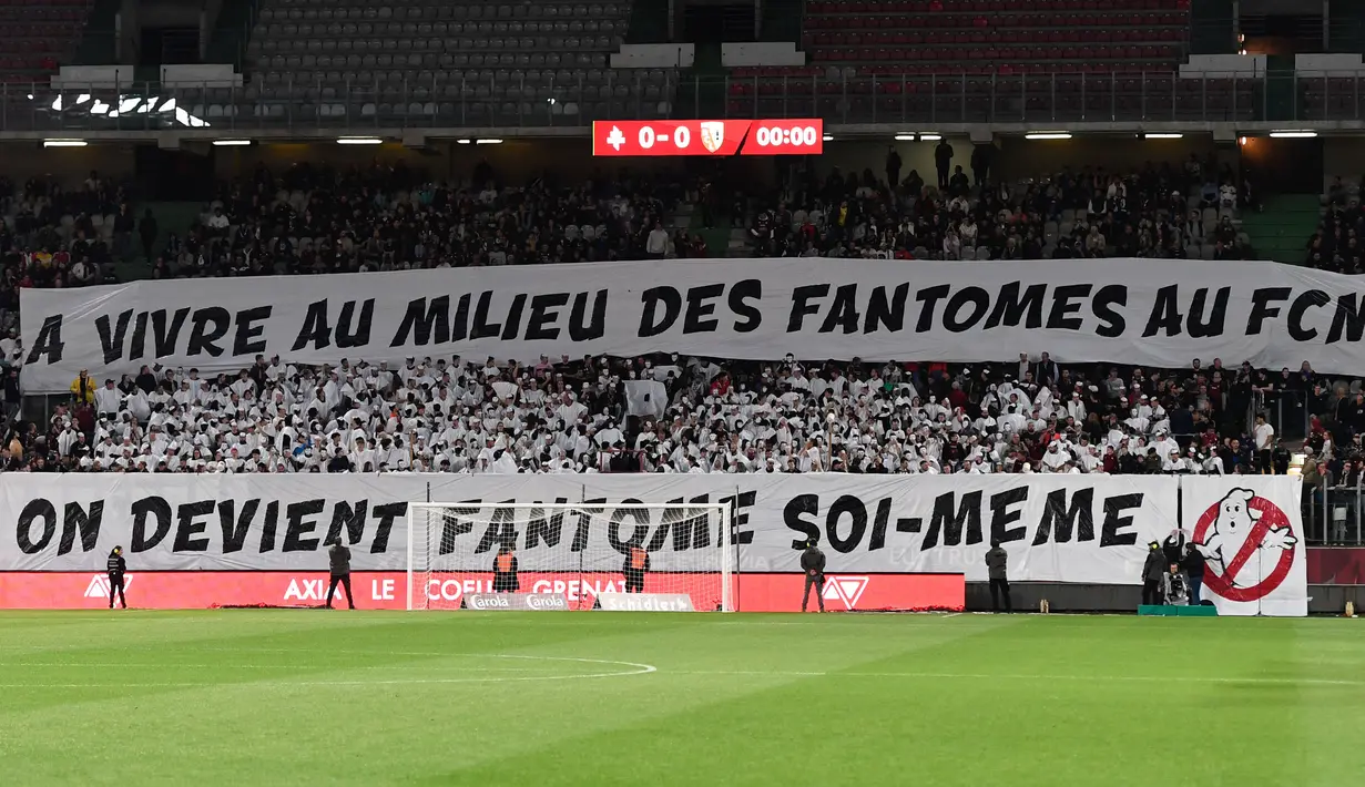 Suporter FC Metz membentangkan spanduk bertulisakan "Saat Anda hidup bersama hantu FC Metz, Anda sendirilah yang menjadi hantu" pada laga lanjutan Liga Prancis 2023/2024 melawan RC Lens di Saint-Symphorien Stadium, Longeville-les-Metz, Prancis, Sabtu (13/04/2024) dini hari WIB. (AFP/Jean-Christophe Verhaegen)