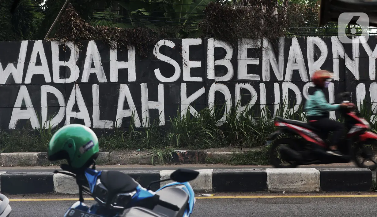 Pengendara melintas di depan mural yang berisi kritikan di Jalan Raya Bogor, Depok, Jawa Barat, Minggu (19/9/2021). Kritik terhadap pemerintah lewat coretan dinding atau mural sempat menjadi polemik karena dihapus. (Liputan6.com/Helmi Fithriansyah)