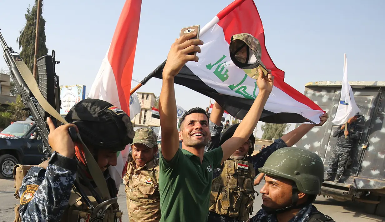 Warga berswafoto dengan polisi Federal Irak  saat merayakan keberhasilan menyingkirkan militan ISIS dari Kota Tua Mosul, Minggu (9/7). Pertempuran Mosul telah meninggalkan sebagian besar kota terbesar kedua Irak itu dalam reruntuhan. (AHMAD AL-RUBAYE/AFP)
