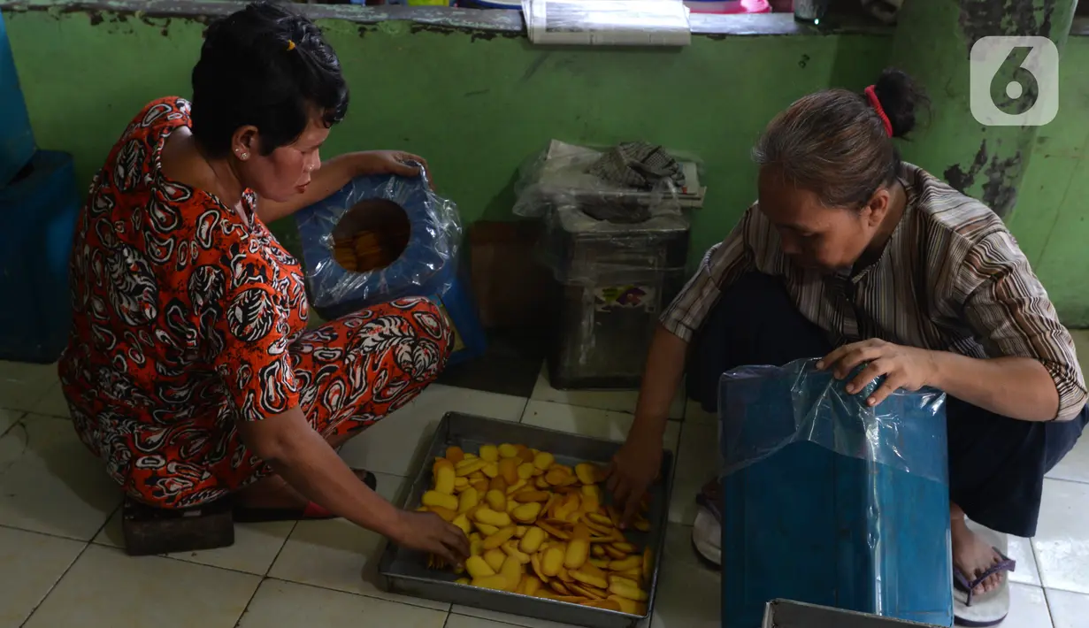Pekerja memasukkan kue kering yang sudah matang ke dalam wadah kaleng di usaha pembuatan kue Pusaka Kwitang di kawasan Kwitang, Jakarta Pusat, Selasa (27/4/2021). Pada masa pandemi COVID-19, usaha milik Hasanudin ini masih memenuhi stok walau tidak banyak permintaan. (merdeka.com/Imam Buhori)