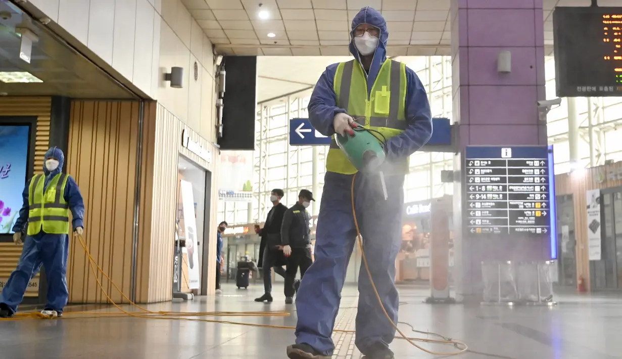 Seorang pekerja mengenakan pakaian pelindung saat menyemprotkan Disinfektan sebagai tindakan pencegahan virus corona COVID-19 di sebuah stasiun kereta api di Daegu, Korea Selatan  (26/2/2020). Jumlah infeksi corona di Korea Selatan melonjak lagi pada Rabu (26/2). (AFP Photo/Jung Yeon-je)