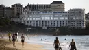 Orang-orang berjalan di pantai di depan tempat pertemuan G7 Le Bellevue di Biarritz, Prancis barat daya 21/8/2019).  Para pemimpin negara-negara G7 akan bertemu Sabtu selama tiga hari di kota resor Biarritz di barat daya Prancis. (AFP Photo/Iroz Gaizka)