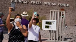 Orang-orang berswafoto dengan termometer di Pos Pusat Pengunjung Furnace Creek, Taman Nasional Death Valley, California, AS, Senin (17/8/2020). Temperatur udara tertinggi di Dunia -- 54,4 derajat Celcius -- tercatat di Taman Nasional Death Valley pada Minggu 16 Agustus. (AP Photo/John Locher)