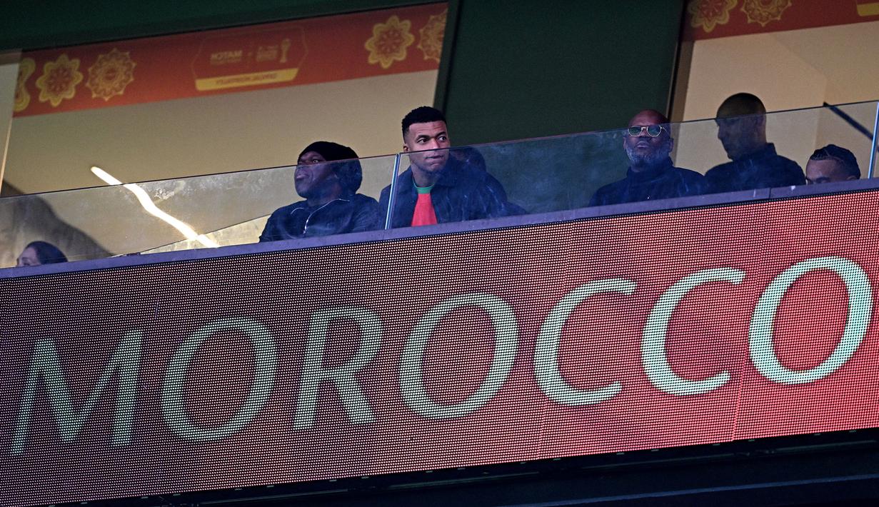 Kylian Mbappe tampak duduk di tribune khusus VVIP dan mengenakan jersey Maroko dengan nomor punggu dua milik Achraf Hakimi. (AFP/Gabriel Bouys)