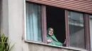 Petugas bantuan Italia Silvia Romano, yang dibebaskan oleh militan Somalia, terlihat di jendela setelah tiba di rumahnya di Milan, 11 Mei 2020. Terkait keputusan menjadi mualaf, Silvia dengan tegas mengatakan telah bersyahadat selama penculikan dan itu pilihannya tanpa paksaan. (AP/Luca Bruno)