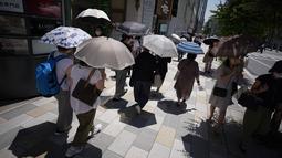 Orang-orang berjalan di trotoar di bawah terik matahari di Tokyo, Selasa (28/6/2022). Pejabat cuaca juga mengumumkan akhir paling awal musim hujan dalam beberapa dekade. (AP Photo/Eugene Hoshiko)