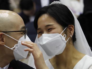 Pasangan memakai masker mengikuti kegiatan nikah massal di Cheong Shim Peace World Center di Gapyeong, Korea Selatan, Jumat, (7/2/2020). Meski memakai masker untuk mencegah virus corona, para pasangan pengantin tampak bahagia di acara tersebut. (AP Photo/Ahn Young-joon)