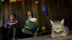 Wanita etnis Kayan saat bersantai di rumah mereka di desa PanPat, Kayan, Myanmar, Rabu (9/9/2015). Kaum perempuan Suku Kayan ini mengenakan banyak kalung berbentuk cincin di lehernya hingga membuat leher mereka panjang. (AFP PHOTO/Ye Aung THU)
