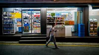 Seorang pria berjalan melewati toko serba ada atau convenience store GS25 di sepanjang jalan di Seoul pada 18 Agustus 2023. (ANTHONY WALLACE / AFP)