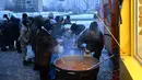 Para sukarelawan dari organisasi amal makanan yang berbasis di Amerika Serikat (AS), World Central Kitchen, membagikan makanan hangat kepada warga setempat di sebuah kawasan perumahan di Kyiv yang mengalami pemadaman listrik dan air akibat serangan Rusia yang menghantam sektor energi, Kamis 22 Januari 2026. Serangan Rusia yang menghantam sektor energi melumpuhkan pasokan pemanas, listrik, dan air di ribuan bangunan permukiman di ibu kota Ukraina, Kyiv, ketika suhu udara turun hingga minus 14 derajat Celsius. (Sergei GAPON/AFP)