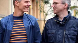 Pasangan Gay Michael (kiri) dan Kai Korok berpegangan tangan di Berlin, (10/10). Pasangan ini menyerahkan sertifikat pernikahan mereka untuk meminta adopsi legal seorang anak laki-laki berusia dua tahun. (AFP Photo/dpa/Britta Pedersen/Jerman Out)