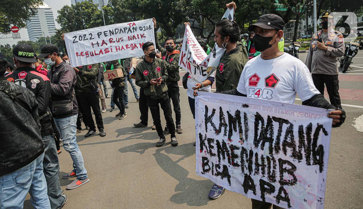 Seorang pengemudi ojek online membentangkan spanduk saat melakukan aksi di kawasan Patung Kuda, Jakarta, Rabu (5/1/2022). Para pengemudi ojek online menuntut Kementerian Perhubungan serta pengelola aplikasi untuk menepati janji kenaikan tarif ojek online. (Liputan6.com/Faizal Fanani)