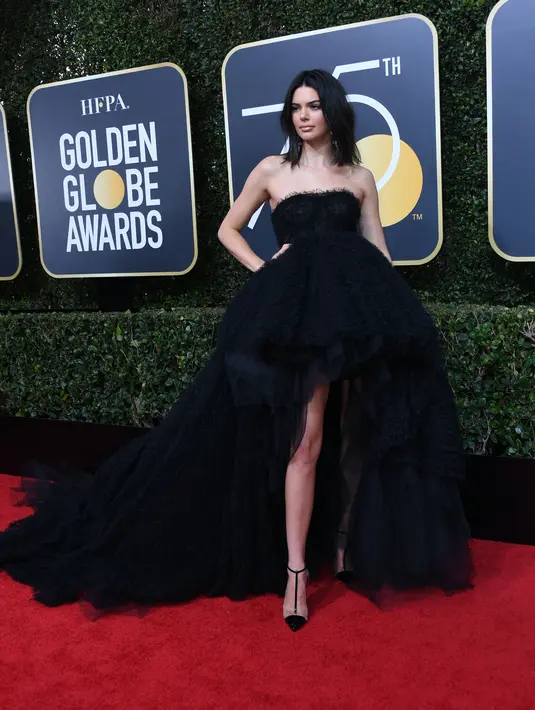 Kendall Jenner berpose di karpet merah ajang penghargaan film Golden Globe Awards 2018 di California, Minggu (7/1). Kendall Jenner berbalut gaun hitam model kemben dengan bagian depan pendek dan ekor gaun yang dibuat panjang. (VALERIE MACON / AFP)