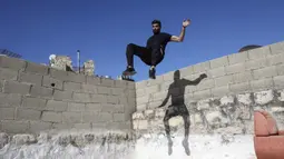 Pemuda Palestina Hammam Abu Sneineh berlatih parkour di atas atap dan tangga rumah batu tradisional di Kota Hebron, Tepi Barat, Sabtu (5/6/2021). (HAZEM BADER/AFP)