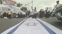 Massa aksi solidaritas kemanusiaan Lampung bersama Palestina jilid II menginjak bendera Israel saat unjuk rasa di Tugu Adipura, Bandar Lampung.  Foto : (Liputan6.com/Ardi).