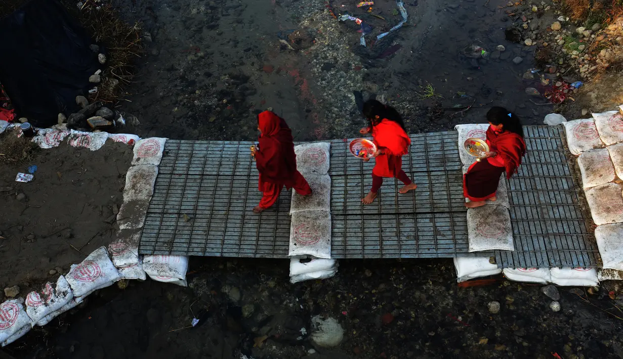 Wanita Hindu Nepal menyebrangi sungai Saali saat festival Swasthani Brata Katha di Kathmandu, Nepal, (24/1). Selama festival umat Hindu Nepal membaca kitab suci Hindu yang didedikasikan untuk dewi Swasthani dan Dewa Siwa. (AFP PHOTO/Prakash mathema)