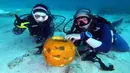 Dua penyelam, Sophie Costa dan Allison Candelmo menunjukkan buah labu dalam Kontes Mengukir Labu Bawah Air, di Cagar Alam Laut Nasional Florida Keys, Florida, Minggu (14/10). Kompetisi diadakan di laut sedalam 9 meter. (Frazier Nivens/various sources/AFP)