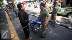 Petugas Satpol PP berdiskusi dengan seorang yang terkena razia yang parkir di kawasan pendestrian Malioboro, (19/4). Petugas memberikan surat peringatan dan mengambil kartu identitasnya yang di tahan di KUPT Malioboro. (Liputan6.com/Boy Harjanto)