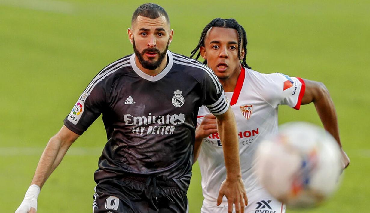 Striker Real Madrid, Karim Benzema, berebut bola dengan pemain Sevilla, Jules Kounde, pada laga Liga Spanyol di Stadion Ramon Sanchez Pizjuan, Minggu (6/12/2020). Real Madrid menang dengan skor 1-0. (AP/Angel Fernandez)