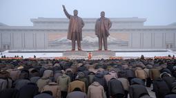 Penduduk Pyongyang memberi hormat di hadapan patung pemimpin Korea Utara Kim Il Sung dan Kim Jong Il selama Hari Peringatan Nasional di Bukit Mansu, Pyongyang (17/12).  Korea Utara tengah memperingati 7 tahun wafatnya  Kim Jong Il. (AFP Photo/Kim Won Jin)