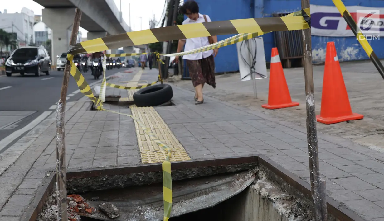 Pejalan kaki melintas di dekat penutup trotoar yang rusak di Jalan RS Fatmawati, Jakarta, Selasa (14/7/2019). Dua buah penutup trotoar di Jalan RS Fatmawati rusak parah, kondisi ini mengganggu kenyamanan dan membahayakan pejalan kaki, terutama pada malam hari. (Liputan6.com/Helmi Fithriansyah)
