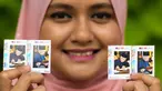 Pekerja pos Nurshafiqa Kasim berpose dengan prangko bergambar PM Malaysia Mahathir Mohamad di sebuah kantor pos di Kuala Lumpur, Selasa (10/7). Prangko bergambar Mahathir ini untuk merayakan ulang tahunnya yang ke-93. (Mohd RASFAN/AFP)