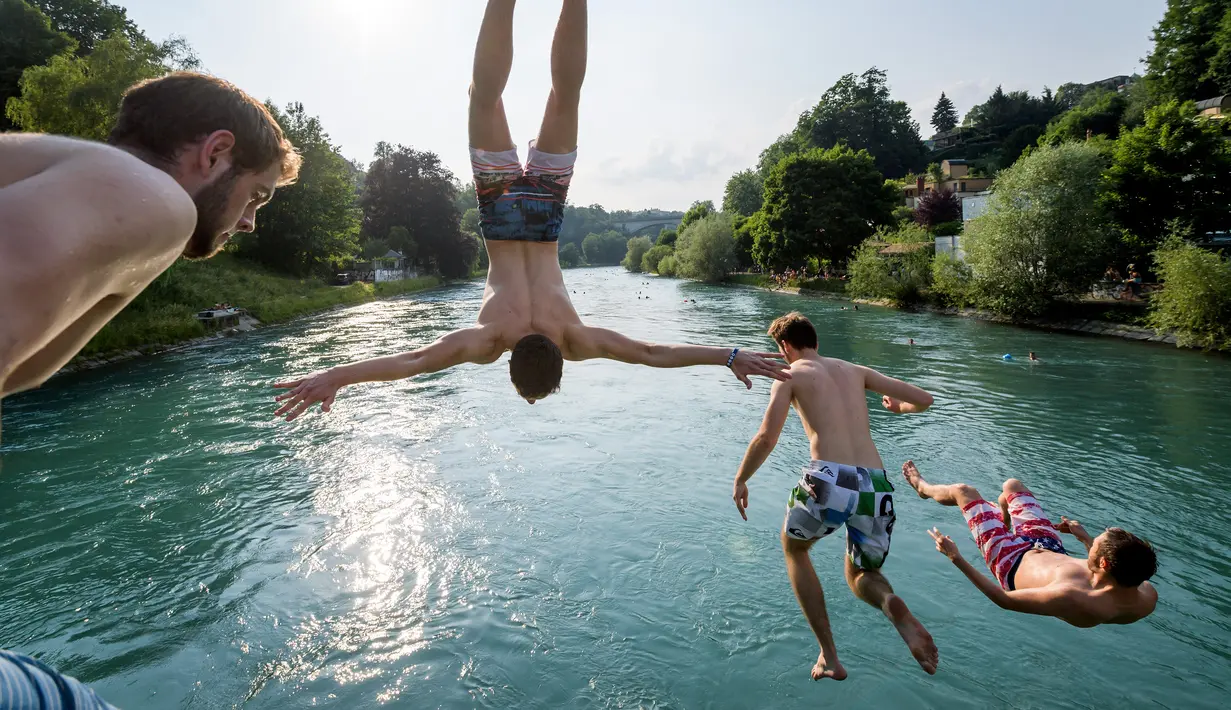 Para pemuda melompat ke Sungai Aare di Bern, Swiss, 21 Juni 2017. Selain panjang dan luas, Sungai Aare juga memiliki kedalaman mencapai 200 meter yang berlokasi dekat Meiringen. (Fabrice COFFRINI/AFP)