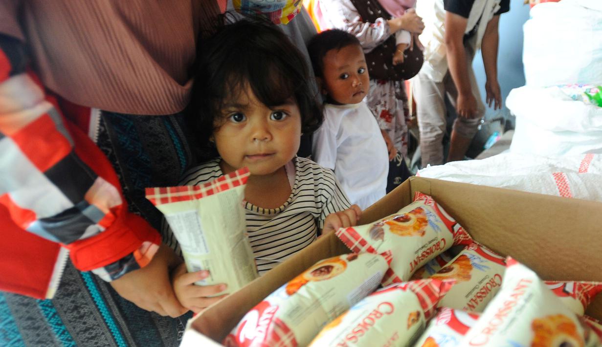 Warga antre mendapatkan pampers dan biskuit bagi anak-anak di Posko pengungsian Mangunkerta, Cianjur, Jumat (23/12/2022). Lebih dari sebulan sejak musibah gempa bumi 5,2 SR sejumlah warga masih tinggal di pengungsian dengan bantuan kebutuhan hidup dari para donatur. (merdeka.com/Arie Basuki)