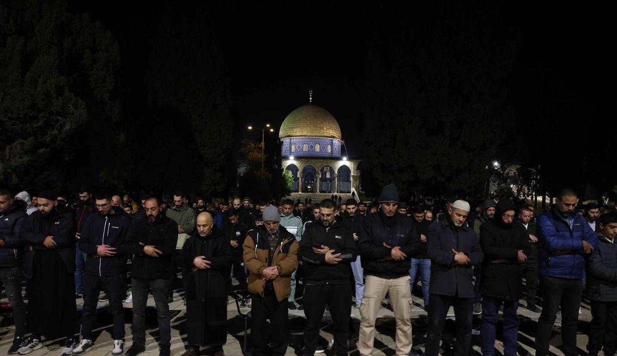 Seperti diketahui, otoritas Israel terus meningkatkan langkah-langkah keamanan, termasuk penangkapan dan larangan sementara terhadap tokoh agama dan aktivis di kota tersebut. Tampak dalam foto, para jamaah Muslim Palestina melaksanakan salat Tarawih pada malam pertama bulan suci Ramadan di dekat Kubah Batu, kompleks Masjid Al-Aqsa, Kota Tua Yerusalem pada 17 Februari 2026. (AHMAD GHARABLI/AFP)