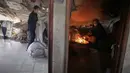 Warga Palestina di Kota Gaza mencoba bangkit dan membangun kembali, melanjutkan hidup meski hidup dalam kekurangan. Tampak dalam foto, Amani Halawa menyalakan api sementara putrinya, Aya, mengatur cucian di rumah mereka yang rusak di Jabaliya, Kota Gaza, Selasa, 25 November 2025. (AP Photo/Jehad Alshrafi)