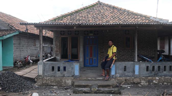 Seorang pria duduk di depan rumahnya di dusun Regahan Lada, Pulau Sebesi, Lampung, Senin (31/12). Banyak warga dusun ini yang bertahan dan enggan meninggalkan rumahnya pascatsunami Selat Sunda pada 22 Desember lalu. (Liputan6.com/Herman Zakharia)