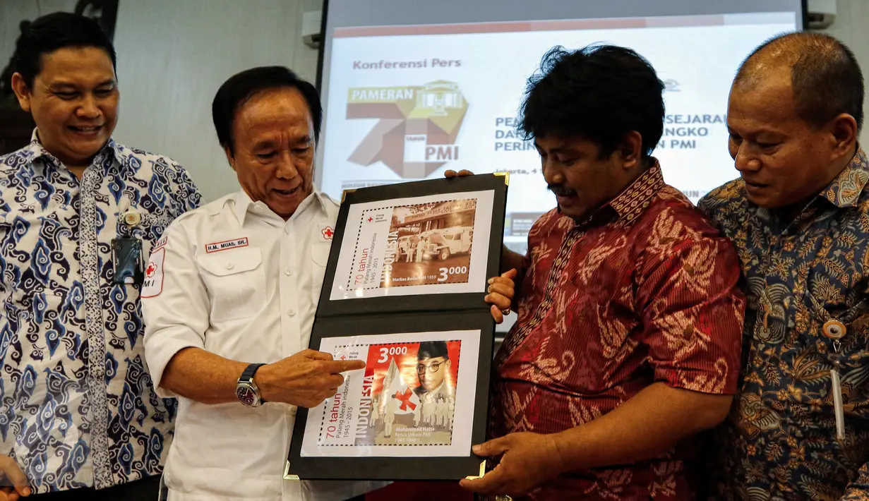 Direktur Filateli dan Properti PT Pos Indonesia, Tata Sugiarta (kiri) dan Ketua Panitia HUT PMI ke-70, Muhamad Muas (kedua kiri) menunjukan gambar perangko perayaan 70 tahun PMI di Museum Nasional, Jakarta,  Jumat (4/9/2015). (Liputan6.com/Yoppy Renato)