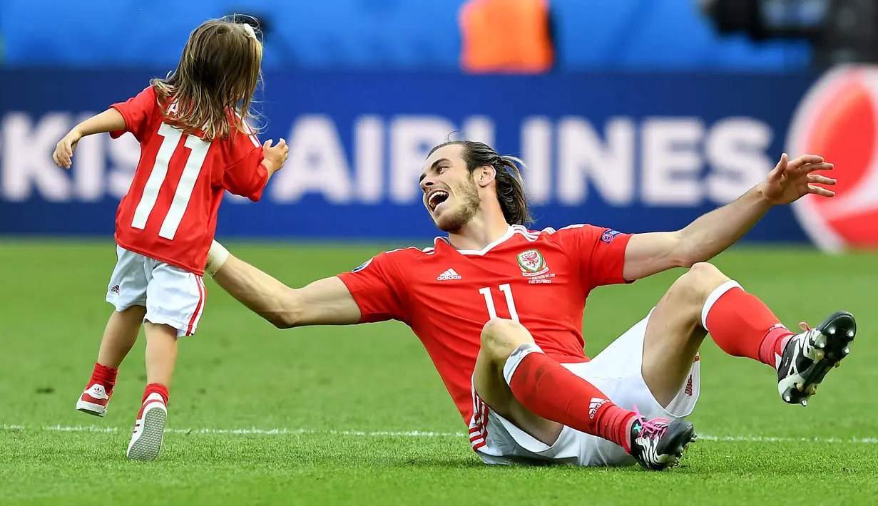 Gareth Bale dan putrinya, Alba Violet bermain ditengah lapangan usai laga melawan Irlandia Utara pada Piala Eropa 2016 di Parc des Princes, Paris, (25/6/2016). Wales Menang 1-0. (EPA/Georgi Licovski)
